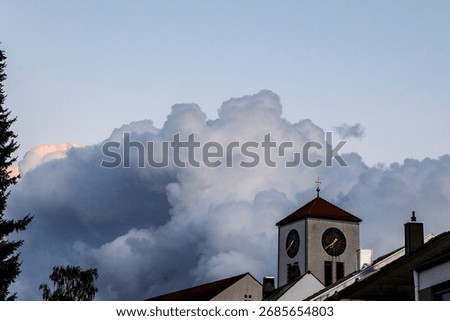Threatening dark storm clouds with a bright pink tip over the church of St Albert in Augsburg Haunstetten