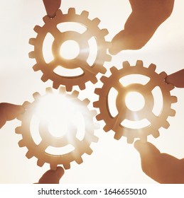 three 3  hands businessman holding gears on the background of blue sky in the sun, connecting the puzzle pieces. creation. mechanism. Business idea concept, teamwork, strategy, innovation, cooperation