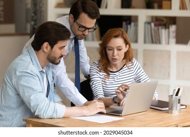 Three 30s colleagues using laptop discussing online presentation, prepare collaborative on-line project, make computer task, share ideas consider strategy, develop start up, plan work sit at workplace - Powered by Shutterstock