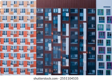 Three adjacent apartment buildings with contrasting modern facades. Patterns of orange, white, brown, blue, green, and pink panels highlight their unique architectural styles. - Powered by Shutterstock