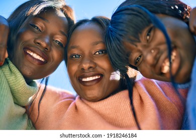 Three african american friends smiling happy hugging at the city.