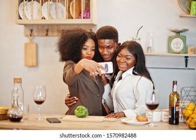 Three African American Friends Spending Time At Kitchen With Wine. Black Peoples Relaxing At Home And Making Selfie On Phone.