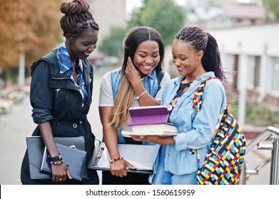 Three African Students Female Posed With Backpacks And School Items On Yard Of University And Look At Tablet.