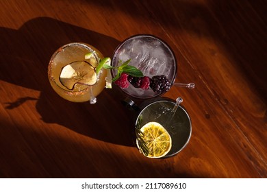 Three Alcoholic Drinks On Top Of A Wooden Table