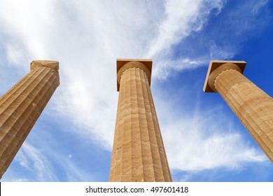 Three Ancient Greek Pillars Against A Blue Sky