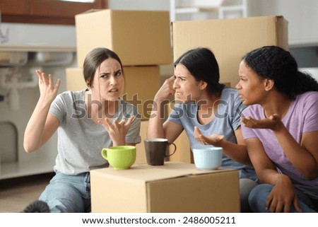 Three angry roommates arguing while moving house in the kitchen