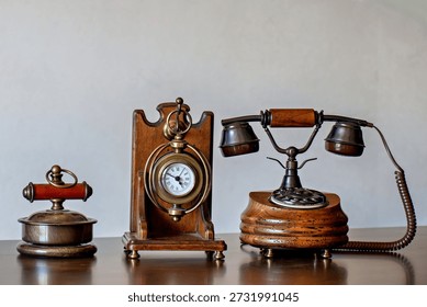 Three antique items on a table: a clock a lamp and a telephone..
