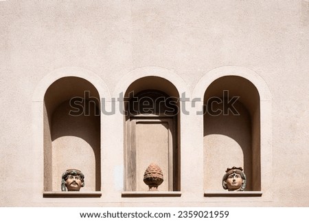 three arched wall niches in a building wall with ornamental sicilian pottery