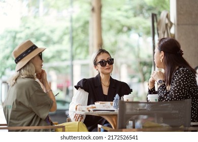 Three Asian Fashion Women Sitting Outside Coffee Shop Drinking And Chatting