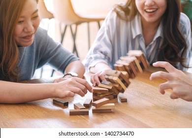 Three asian friends sitting and playing Tumble tower wooden block game together with feeling happy - Powered by Shutterstock