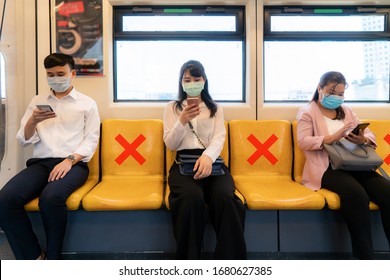 Three Asian people wearing mask sitting in subway distance for one seat from other people keep distance protect from COVID-19 viruses and people social distancing  for infection risk

