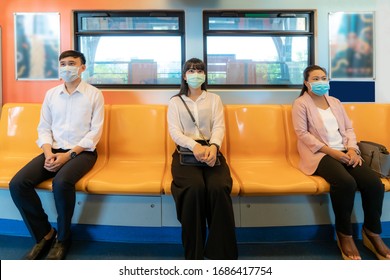 Tres asiáticos con mascarillas sentados a una distancia del metro para un asiento de otras personas mantienen la distancia protegerse de los virus COVID-19 y de las personas que se distancian socialmente por el riesgo de infección 
