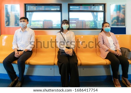 Three Asian people wearing mask sitting in subway distance for one seat from other people keep distance protect from COVID-19 viruses and people social distancing  for infection risk 
