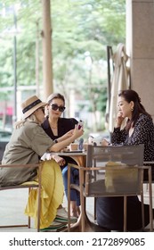 Three Asian Women Sitting Outside Coffee Shop Drinking And Chatting