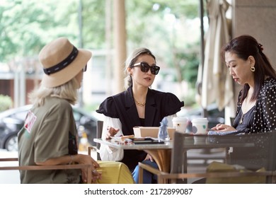 Three Asian Women Sitting Outside Coffee Shop Drinking And Chatting