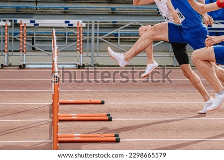 three athlete runners running together 100 meters hurdles race in summer athletics championships