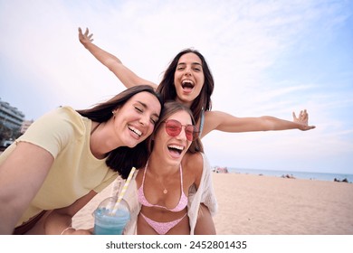 Three of attractive Caucasian women making a selfie doing piggyback looking excited at camera on summer day. Nice female friends enjoy their holidays on Mediterranean beach of Spain. Portrait.  - Powered by Shutterstock