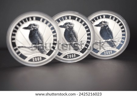 Three Australian 2009 1 ounce silver kookaburra coins standing in a row on a black background