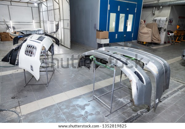 Three auto bumpers\
 parts are installed on the racks after painting in the car repair\
shop in the room with tools and equipment for repairing body parts\
after an accident