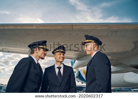 Three aviators having a conversation by a landed jetliner