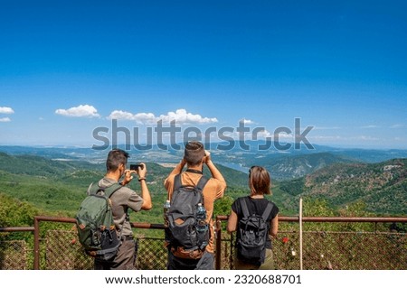 Three backpackers photographing the landscape from Dobogókő Lookout, Hungary