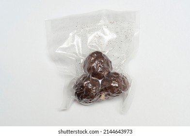three balls of Belper Knoll cheese in vacuum packaging on a white background. Hard Swiss cheese in the form of small balls, sprinkled with black pepper. top view.