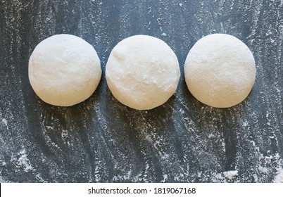 Three balls of fresh homemade wheat dough on kitchen table. Home baking. Dough for pizza cooking, pasta dumplings or bread.Horizontal.