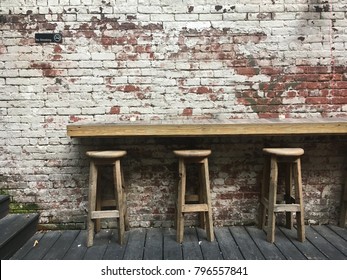 Three Bar Stools In The Backyard Of A Pub In New York. Grungy Brick Wall With Peeling Paint With A Sign Which Says Please Be Courteous To Our Neighbors. Hip Back Garden Of A Bar In The City, No People