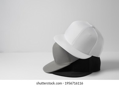 Three baseball snapback hats in monochrome black, white and gray colors stacked on top of each other isolated over white background. Empty cap design template. Horizontal shot