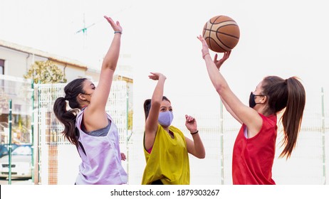 three basketball players jump up to catch the ball wearing masks - Powered by Shutterstock