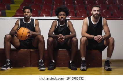 Three basketball players sitting on a bench watching the game. - Powered by Shutterstock