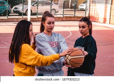 Three Basketball Players Touch The Ball. Friendship Is Present.