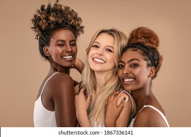 Three Beautiful Diverse Girls Posing together, smiling and looking at camera. Facial Skincare. Group of happy multiethnic woman posing in studio.