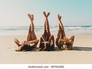 Three beautiful girls on the beach lying on the sand