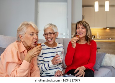 Three Beautiful, Mature Women Are Sitting At Home And Drinking Brandy. They Are Having Fun, Laughing And Updating Each Other On The Latest News. Women Are Between 50 And 65 Years Old. Cheers!