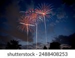 Three beautiful multi-colored fireworks exploding in the sky at dusk against partially blue cloudy skies. Copy space.
