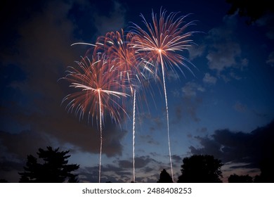 Three beautiful multi-colored fireworks exploding in the sky at dusk against partially blue cloudy skies. Copy space. - Powered by Shutterstock
