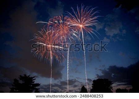 Three beautiful multi-colored fireworks exploding in the sky at dusk against partially blue cloudy skies. Copy space.