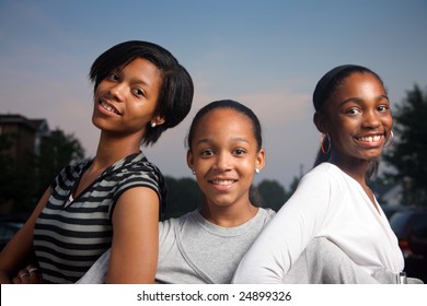Three beautiful smiling teenage African American girls outdoors