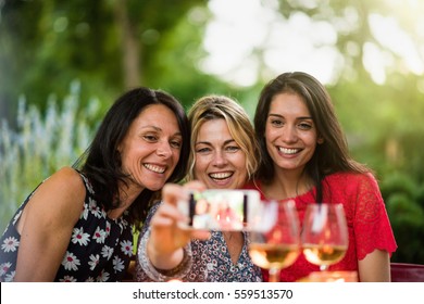 Three Beautiful Women Having Fun By Taking A Selfie On A Terrace By A Summer Evening