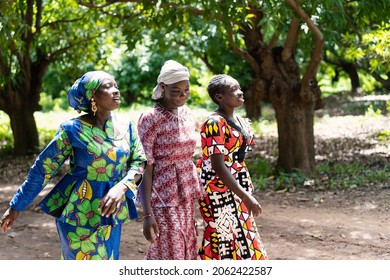 Three beautiful young black women with colourful festive clothing walking side by side on a forest path, singing a traditional African song - Powered by Shutterstock