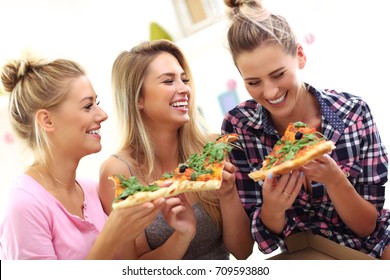 Three Beautiful Young Women Eating Pizza At Home