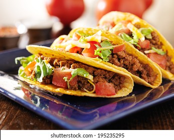 three beef tacos with cheese, lettuce and tomatoes - Powered by Shutterstock