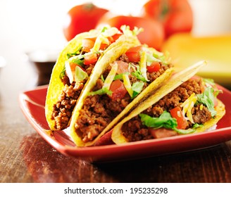 three beef tacos with cheese, lettuce and tomatoes - Powered by Shutterstock