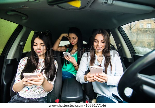 Three best friends in the car and use smart phone\
while drive car