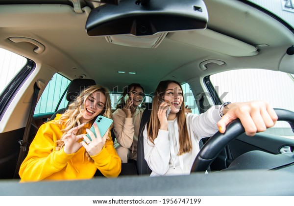 Three best friends in the car and use smart phone\
while drive car