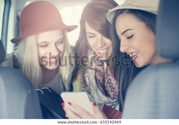 Three best friends riding in the car. Three\
best friends in the car and riding ridiculous message. Girl showing\
her friends messages.