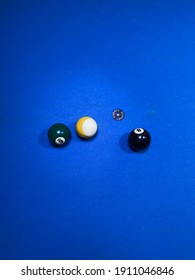 Three Billiard Balls In Black With Number Eight, Yellow, And Green With Number Six On The Blue Pool Table Taken From Above