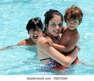 Three Biracial Siblings Having Fun In A Community Swimming Pool.