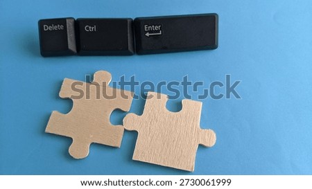 Three black computer keys labeled "Delete," "Ctrl," and "Enter" are aligned above two wooden puzzle pieces.